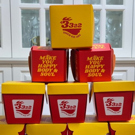 A pyramid of red and yellow 3322 Chicken Rice Cups take-out boxes